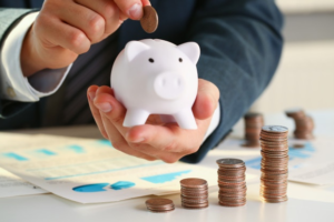 Businessman counting his change while looking at graphs to determine revenue vs proft