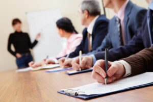 Row of business people making notes during a presentation of an indisputable ERP business case