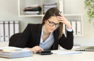 Woman using calculator and paper to fill in the gaps in her accounting process because she isn't using ERP software