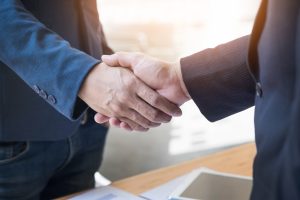 Two buisiness people shaking hands indicating they have made a deal