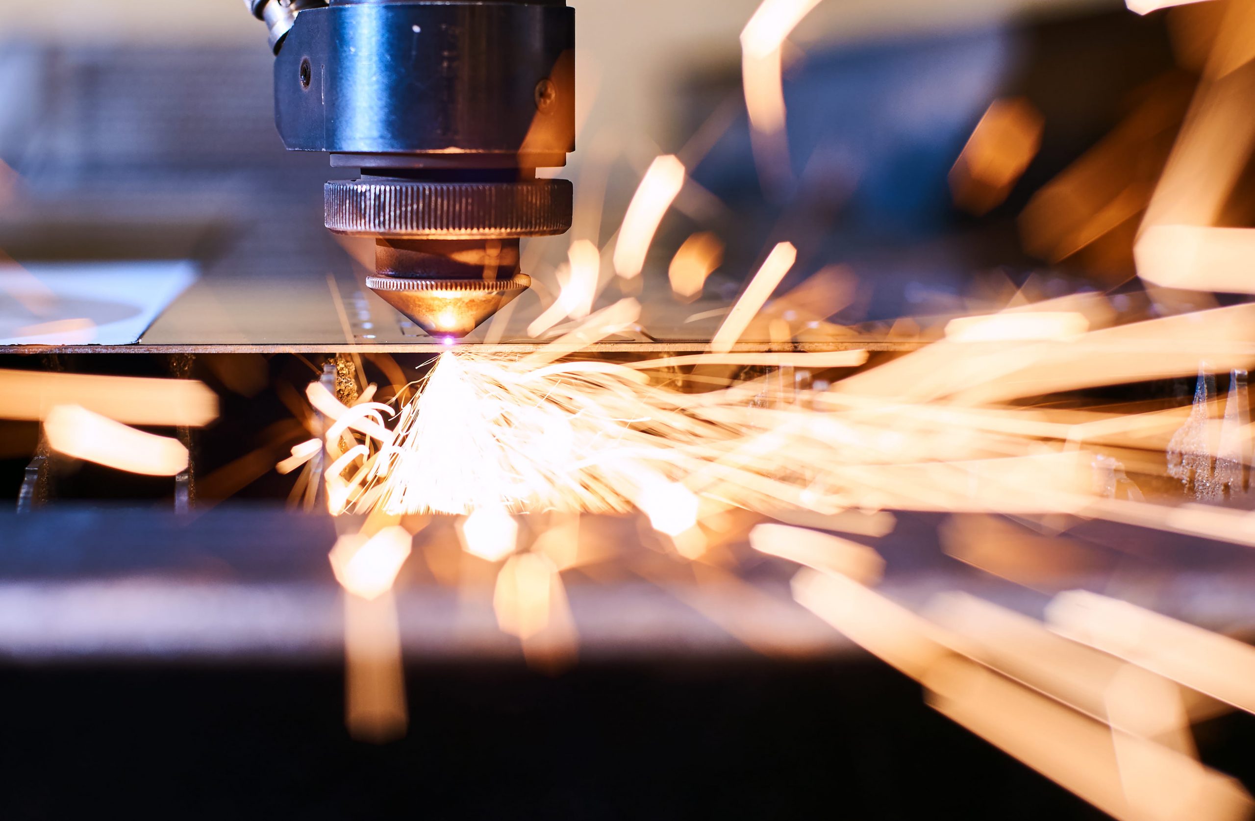 Close up of using a laser to cut metal with sparks flying