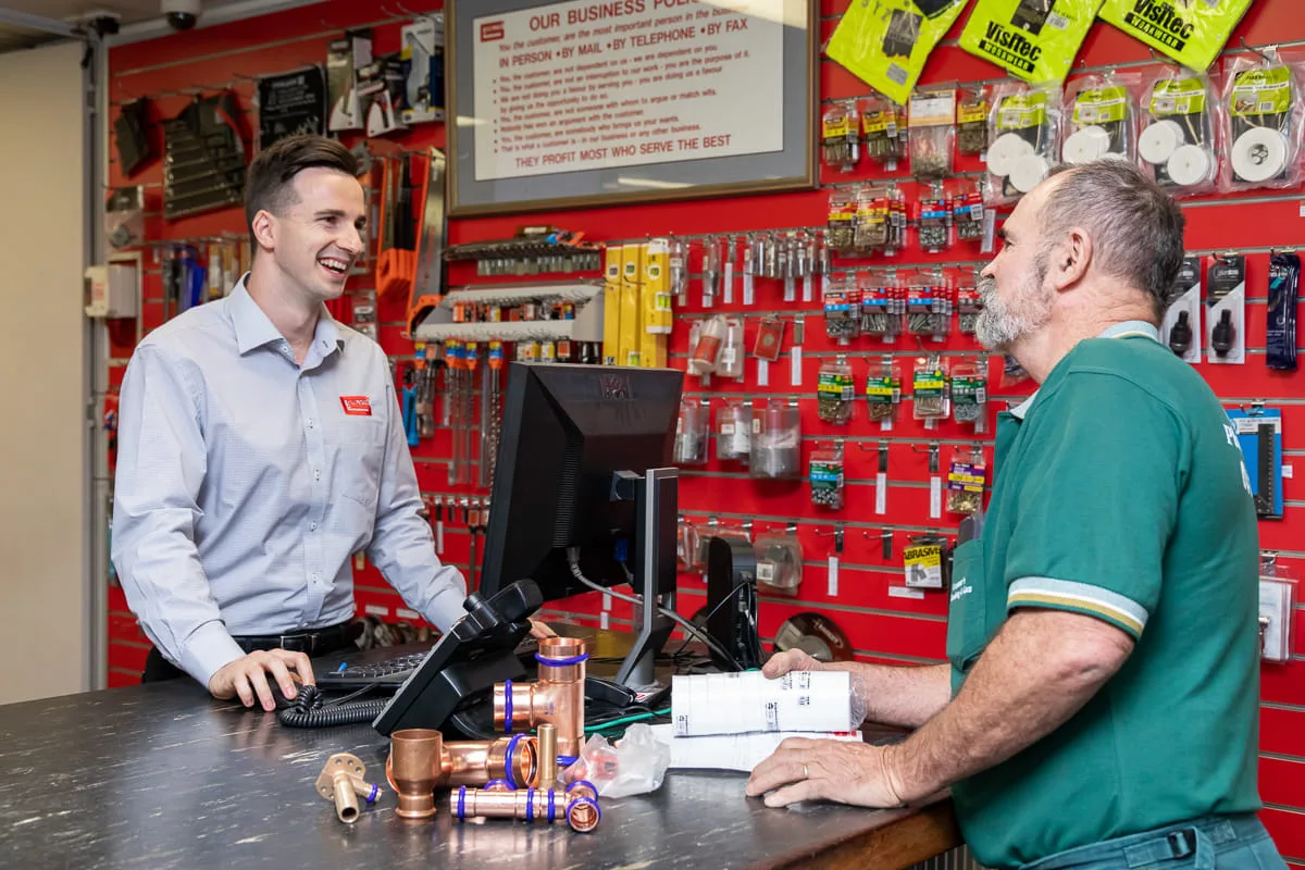 A Galvins employee serving a tradesperson at the sales counter who is purchasing various copper plumbing products