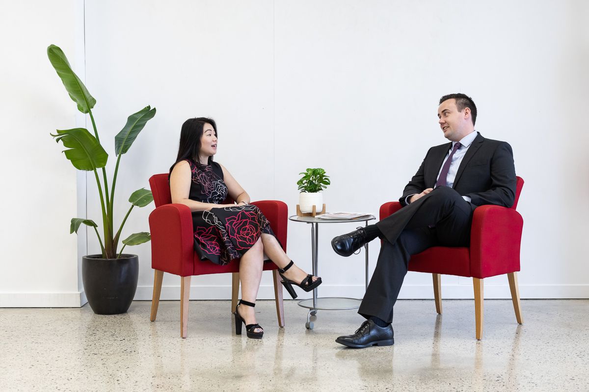 Two Precise employees Lily and Callum sitting in red chairs and having a conversation