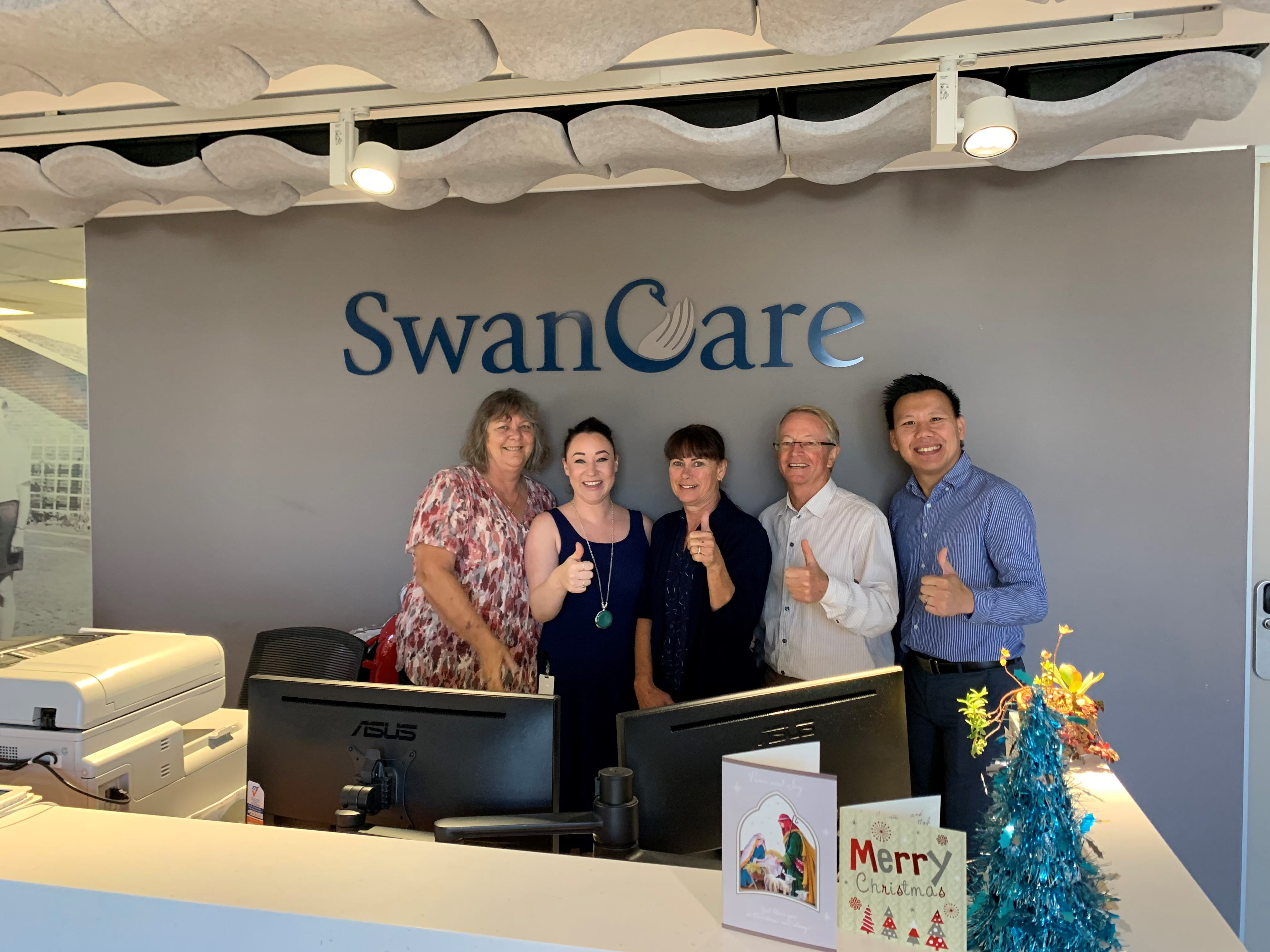 Swan Care team giving the thumbs up beneath their sign