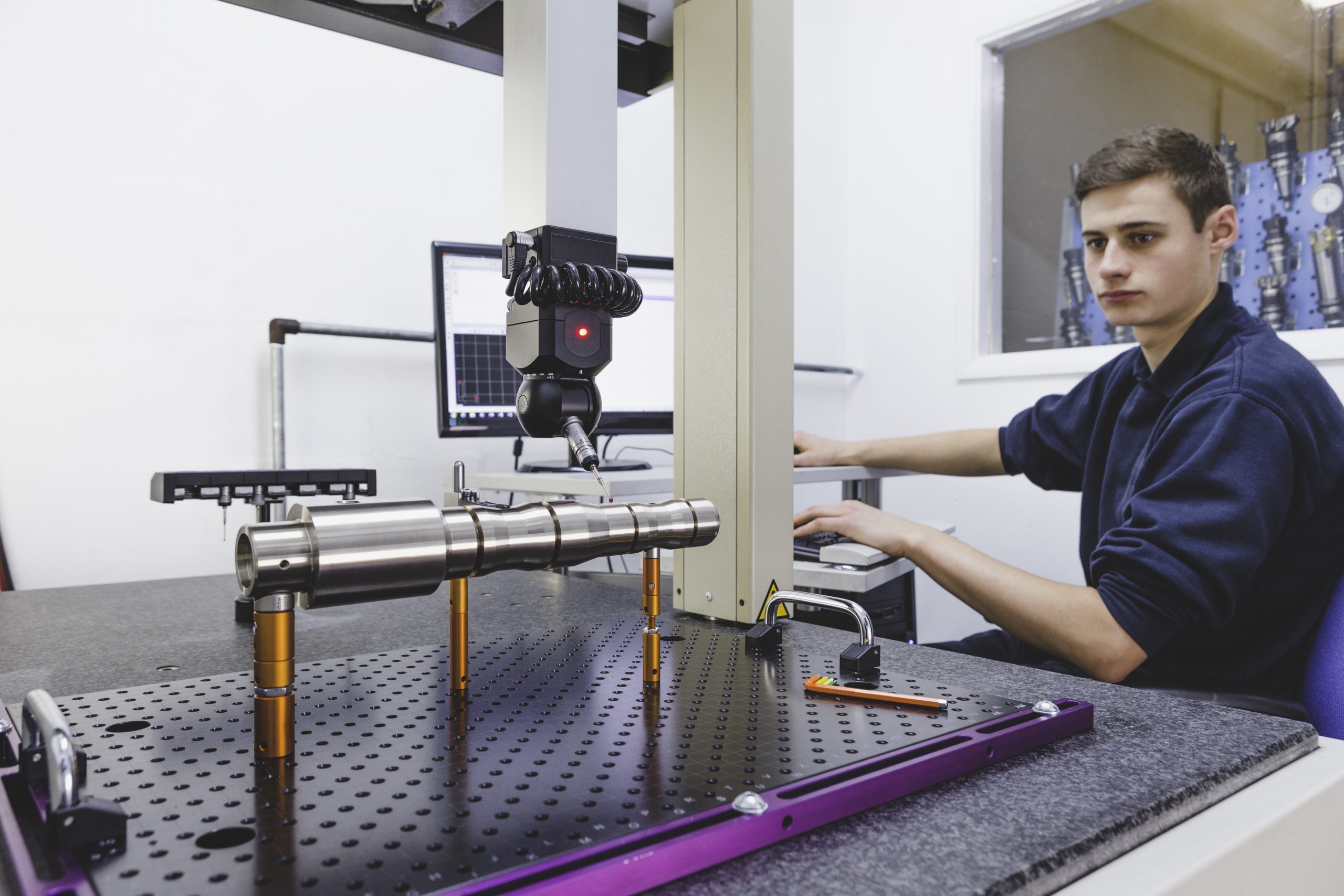 Young man using a coordinate measuring measure to configure a part to order