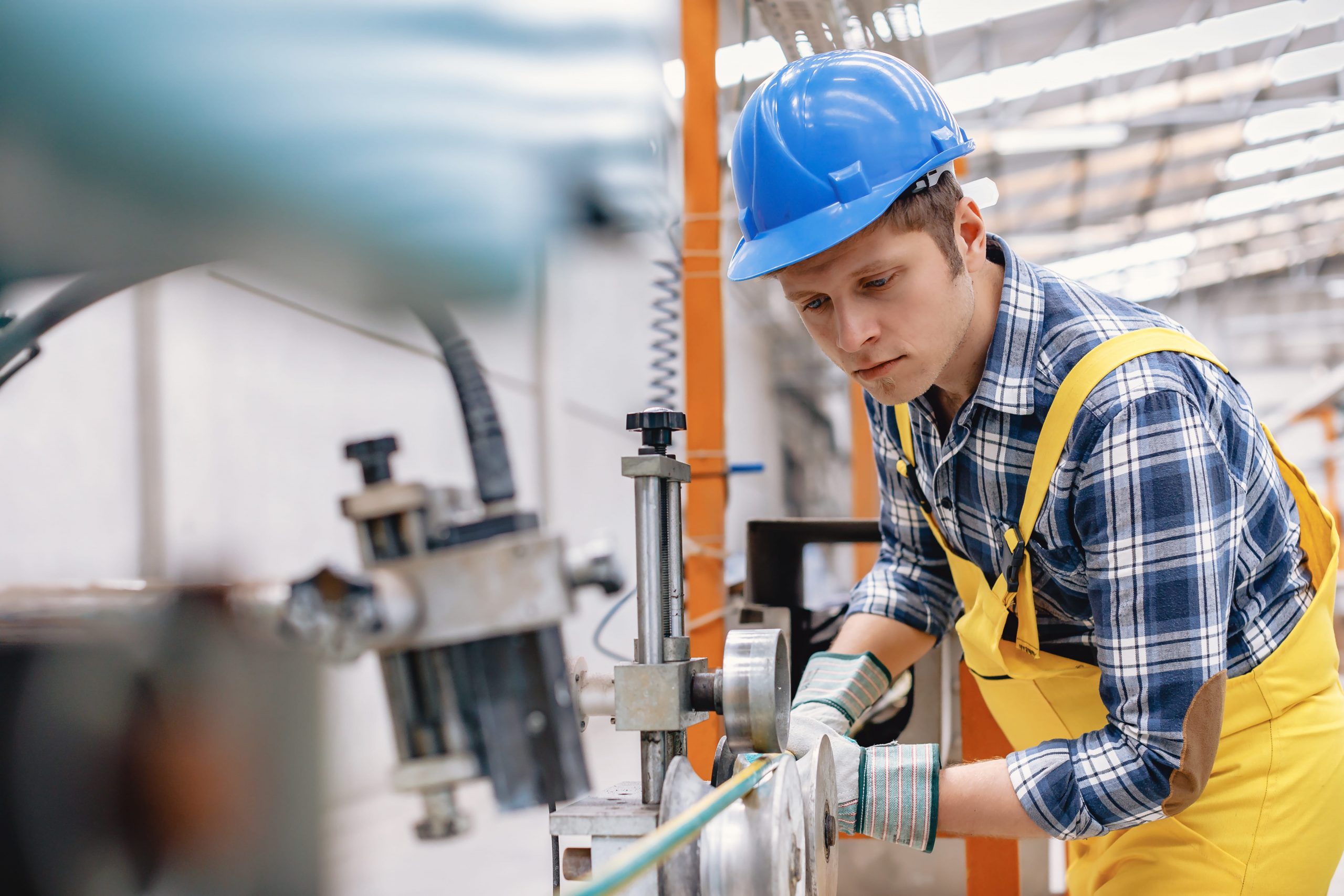 Young worker making stainless steel cable meter wire roll and working in a large factory warehouse