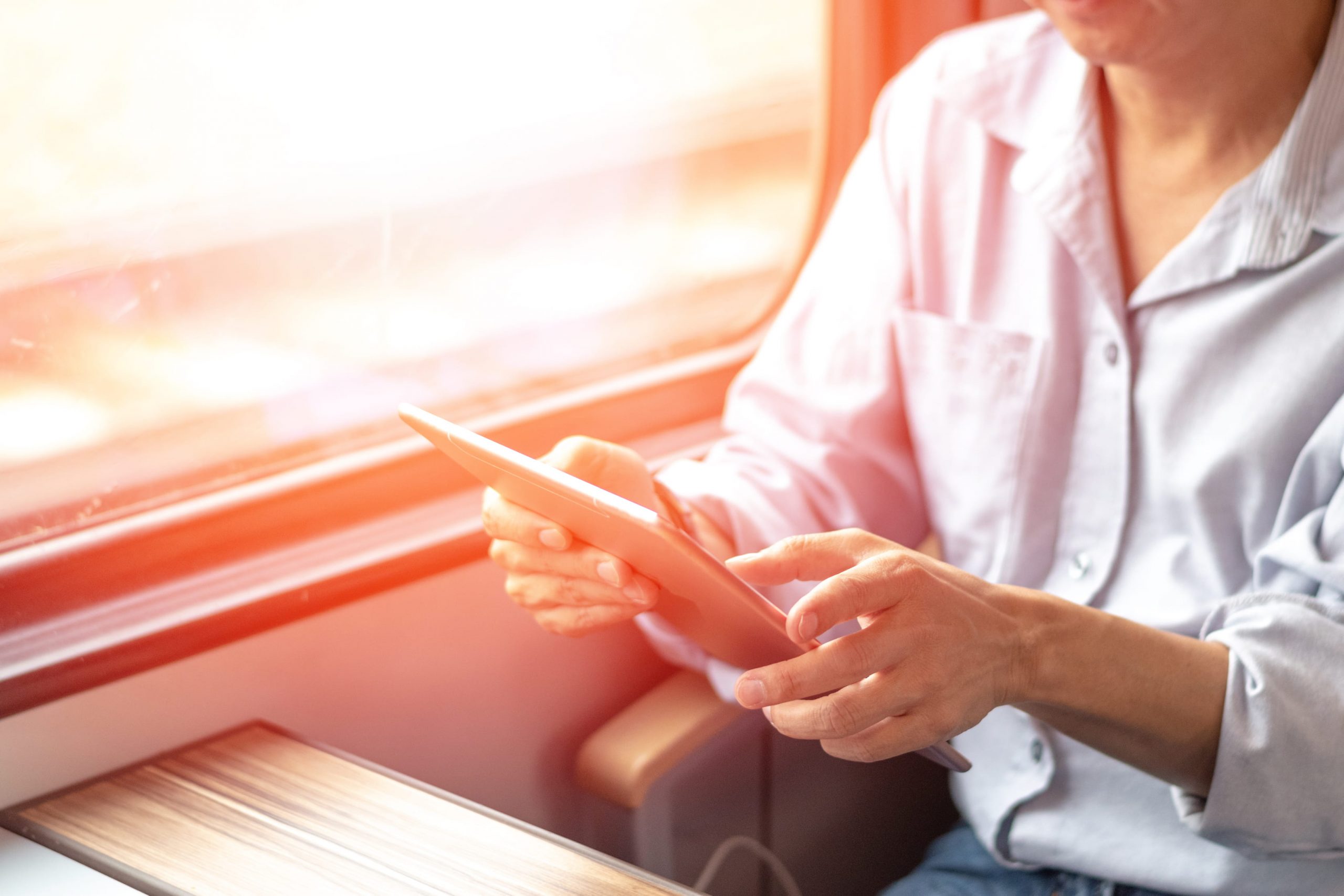 Person using a tablet to access reporting remotely on train commute into work